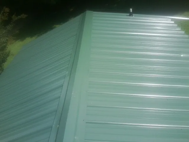 New green metal panels meeting at the ridge of a roof — Flat Roof Repair work by our crew in Lowry