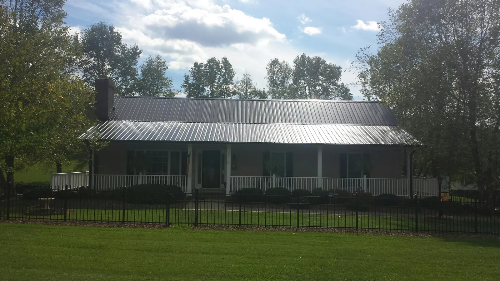Gray metal roof on a brick ranch with a full width front porch — Gutter Guard Installation work by our crew in Lowry
