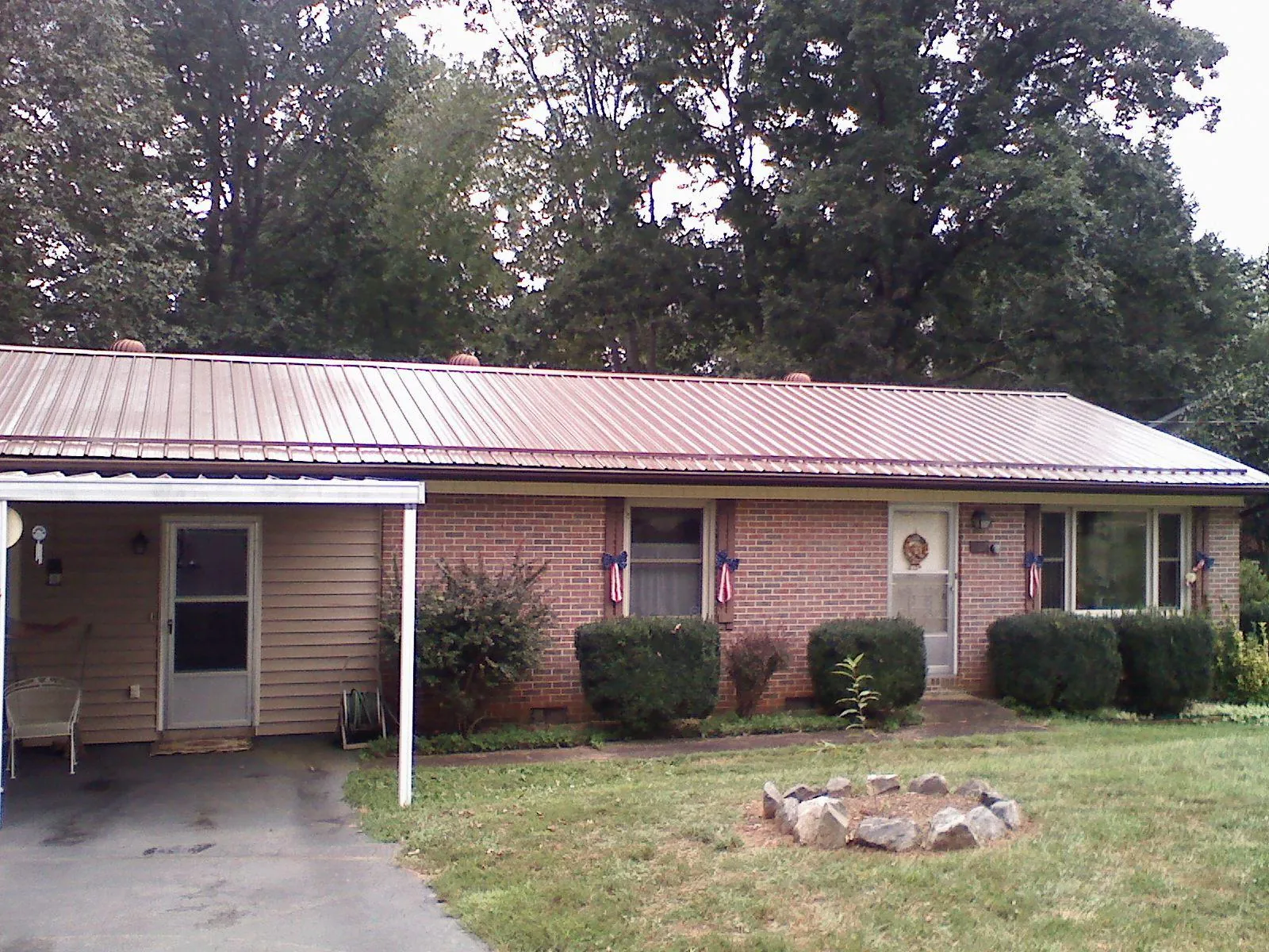Bronze metal roof and carport on a brick ranch home — Roof Repair work by our crew in Lowry